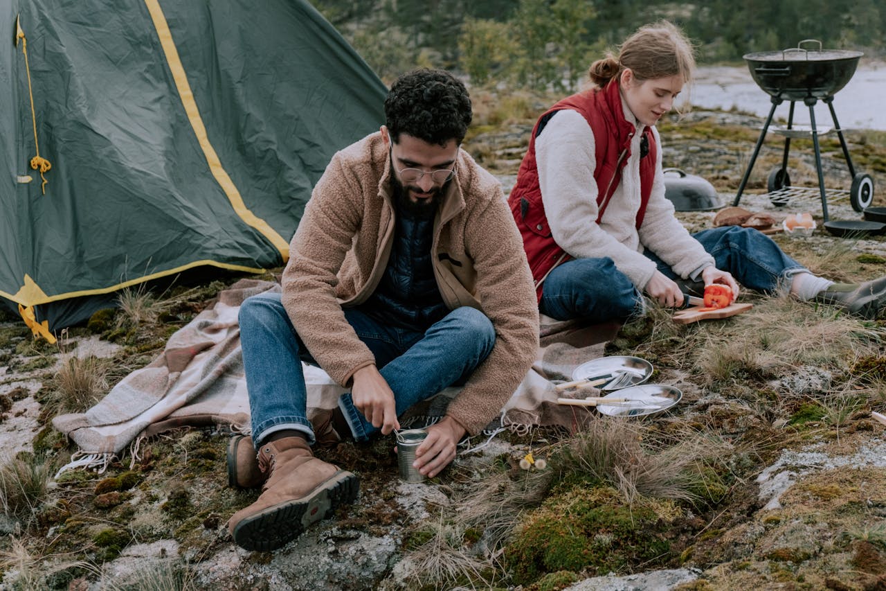 services-01 Couple enjoying a camping trip, preparing food next to their tent outdoors.